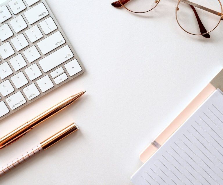 Frau mit schulterlangem braunem Haar, trägt ein weißes Oberteil mit Rüschendetails.