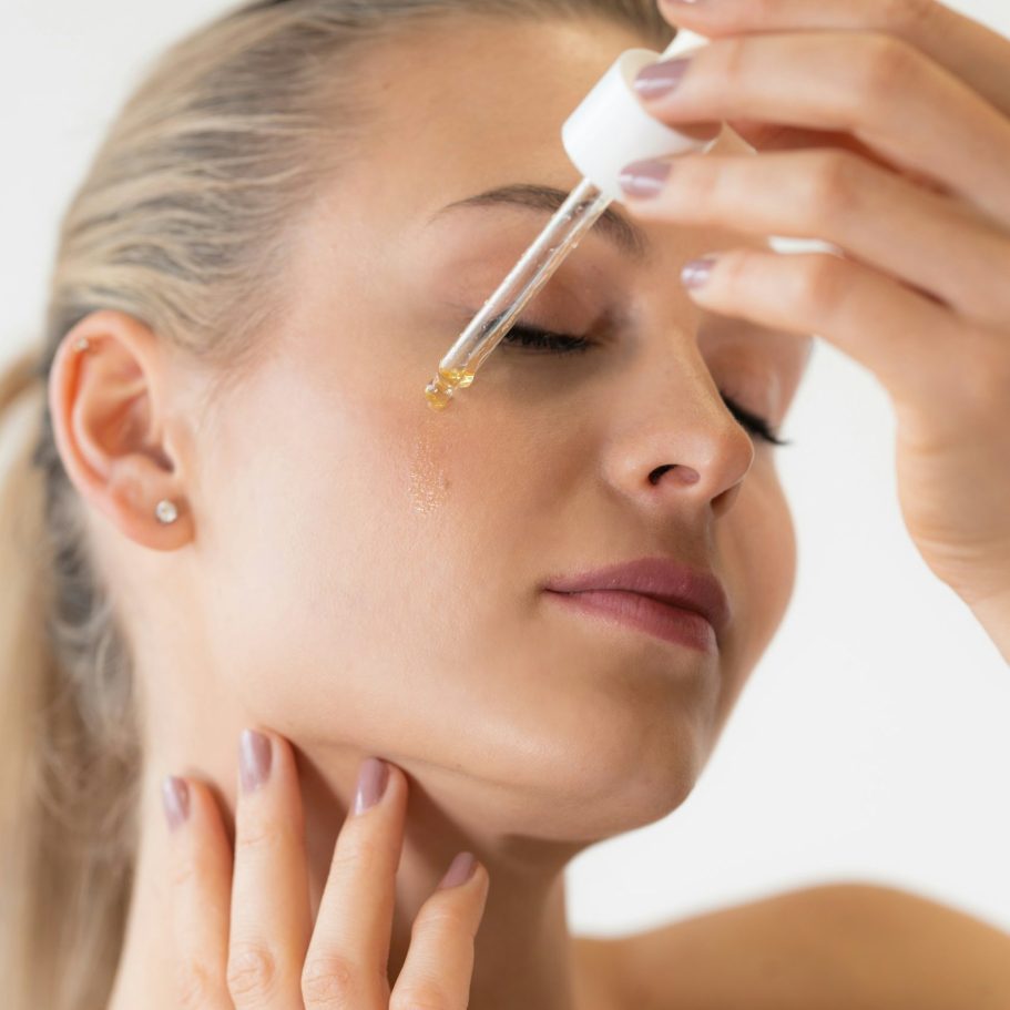 Frau trägt mit einer Pipette ein Hautpflegeserum auf ihr Gesicht auf