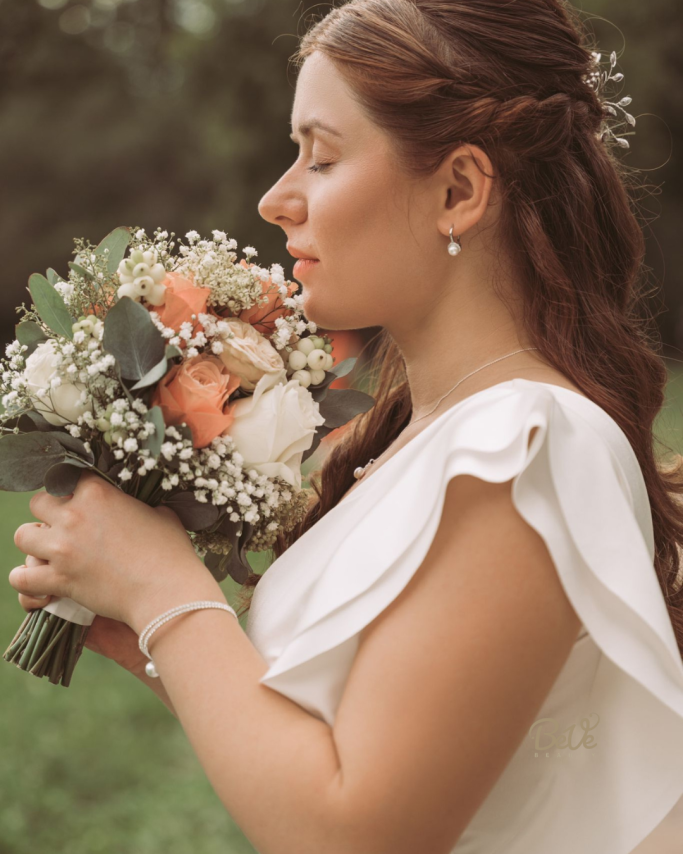 Braut im Seitenprofil mit Blumenstrauß und abgestimmtem Hochzeits-Make-up