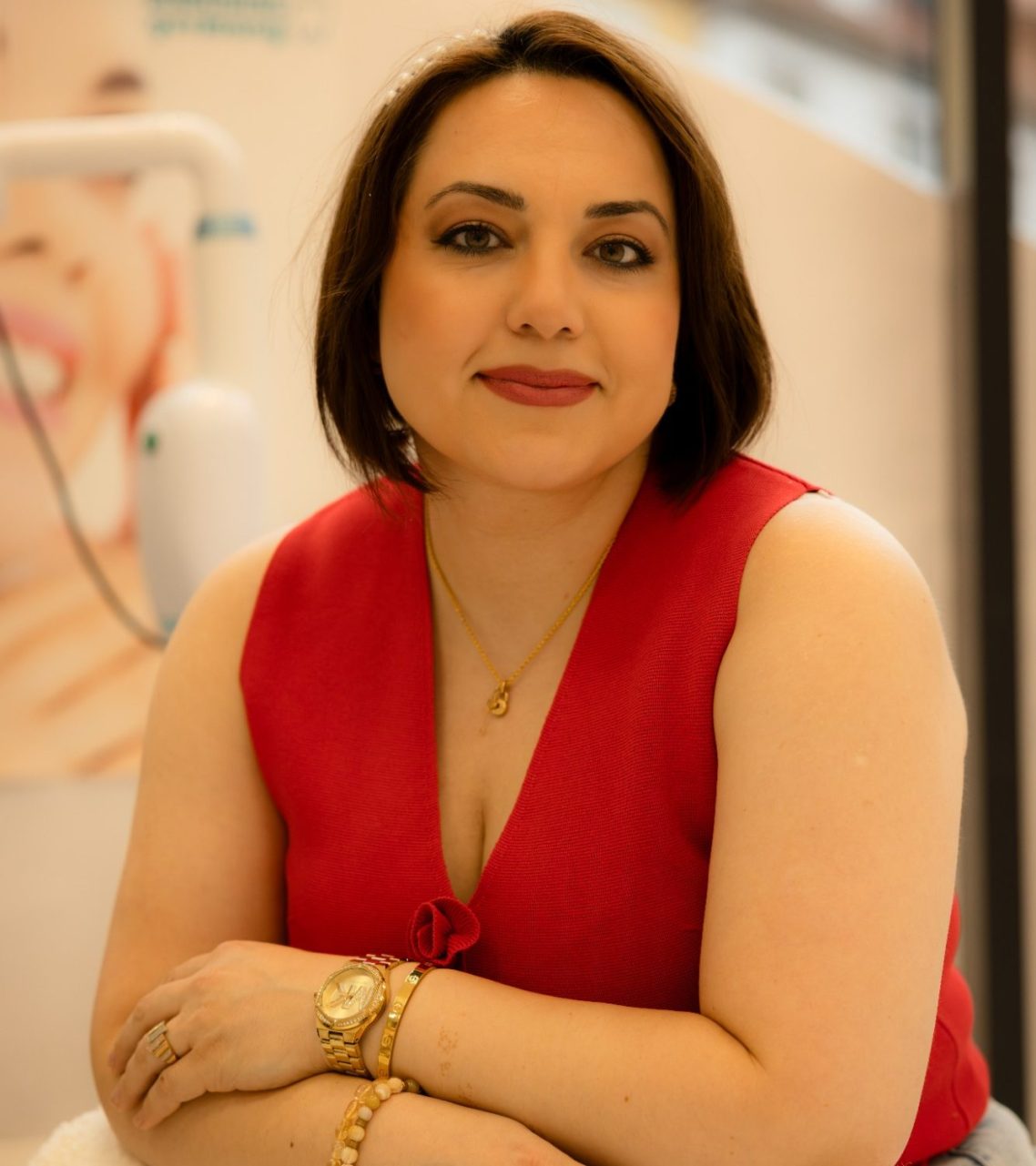 Frau mit kurzem braunem Haar in rotem Oberteil, lächelt freundlich und posiert.