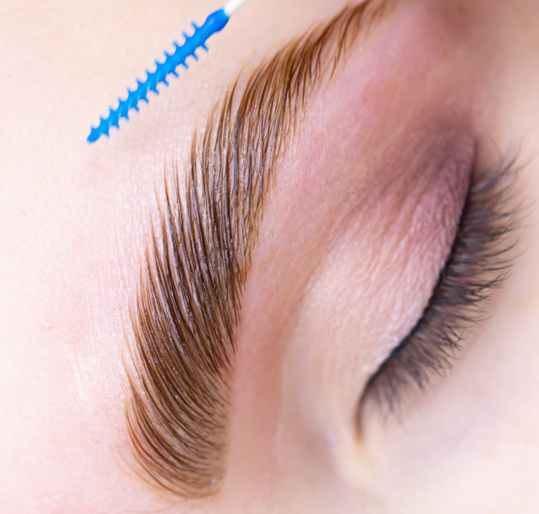 Nahaufnahme eines Auges mit geformter Augenbraue und Wimpernbürste.